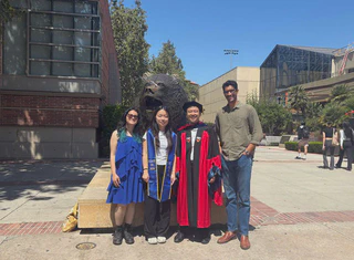 Tanya Wang wearing a UCLA Class of 2026 stole with Tanigawa Lab members in front of the UCLA Bruin Bear statue.