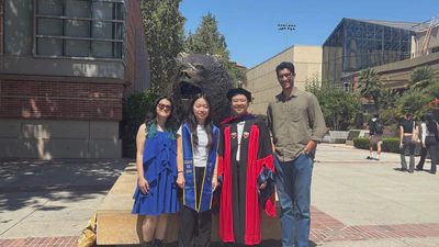 Tanya Wang wearing a UCLA Class of 2026 stole with Tanigawa Lab members in front of the UCLA Bruin Bear statue.